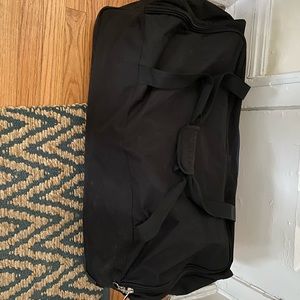 Large black wheeled luggage. Brand: Adolfo